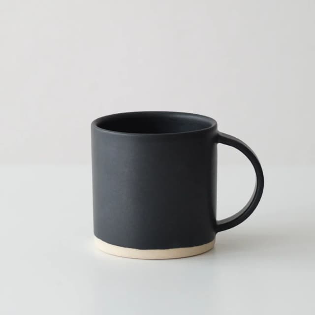 Black porcelain mug with modern square handle and natural clay accents on rim and bottom.